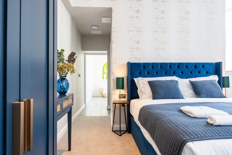 A bedroom at Above Hotels with a blue velvet headboard